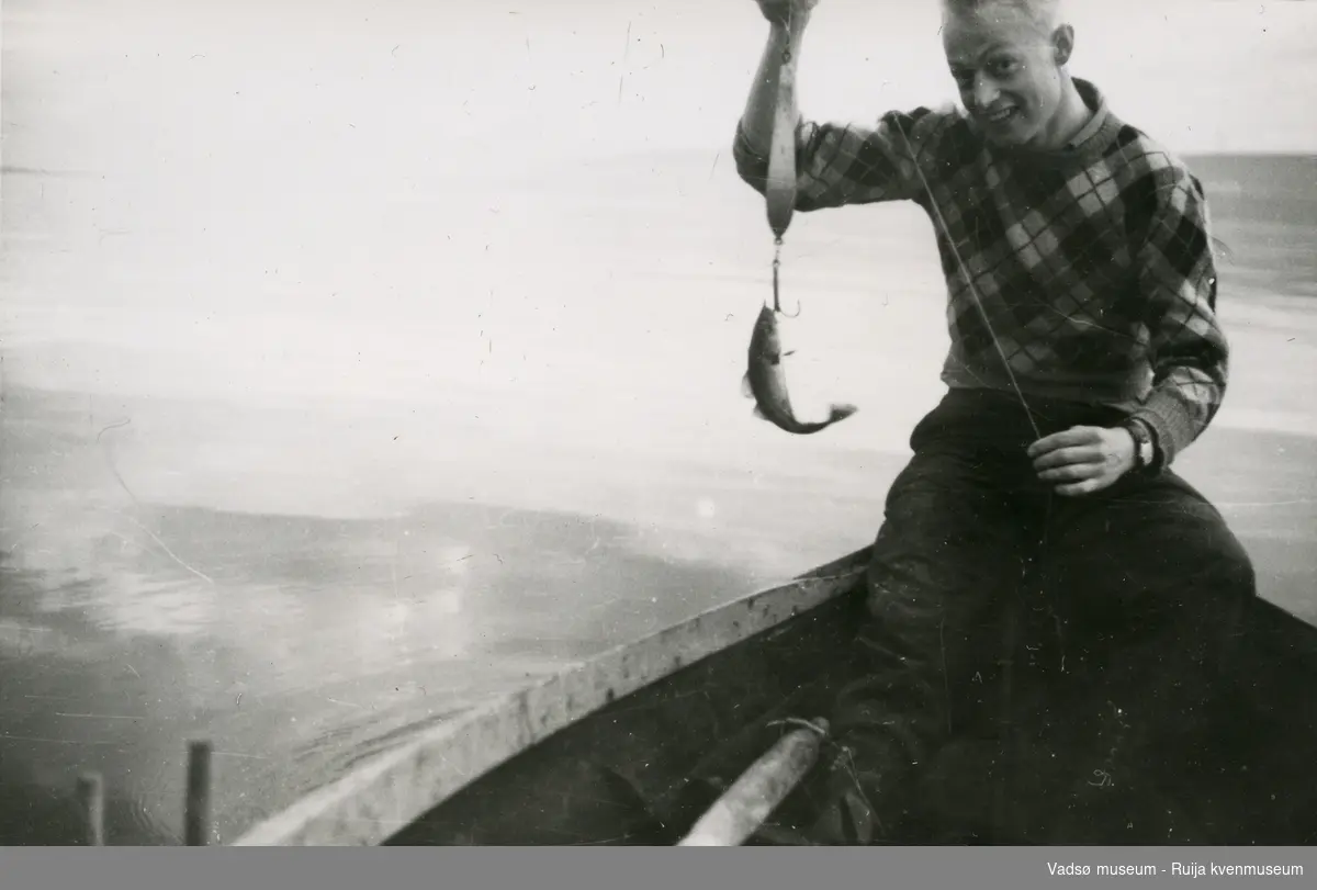 Aldrik Methi er ute å fisker vest for moloen i Vadsø, 1950. Her har han fått en liten sei på kroken. 
