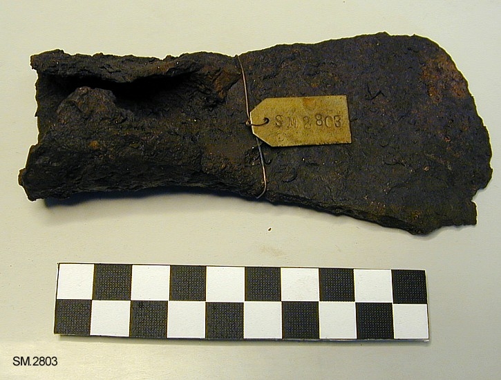 Celt av jern, av form som Jan Petersen: 1.c. fig. 93, altså forholdsvis liten, med åpen fal og jevnt svinget blad med buet egg. 