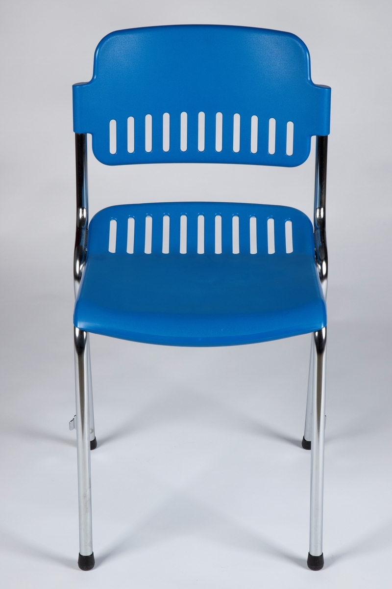 Stol med ramme i forkrommet metall og med åpen rygg. Sete og rygg i støpt, blå plast (polypropylen). Stolen er enkelt ergonomisk formet med 12 gjennombrutte rifler innerst på setet og nederst på ryggen. Stolen kan stables og har feste på hver side av bakbena for side-hekting av stoler i rekke.