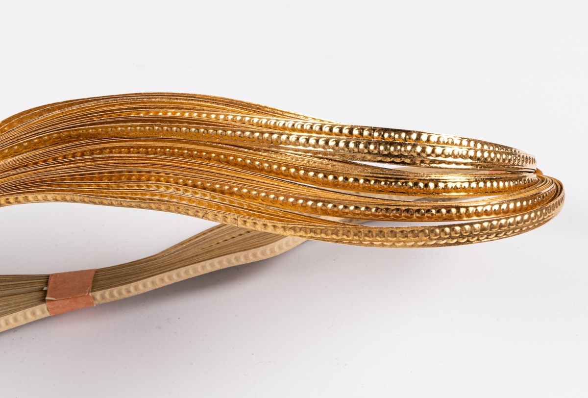 Bunt med guldfärgade pappersband som använts för dekor av omslag av konfekt.