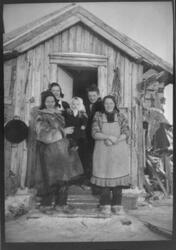 Samisk kvinne med barn i døråpningen.