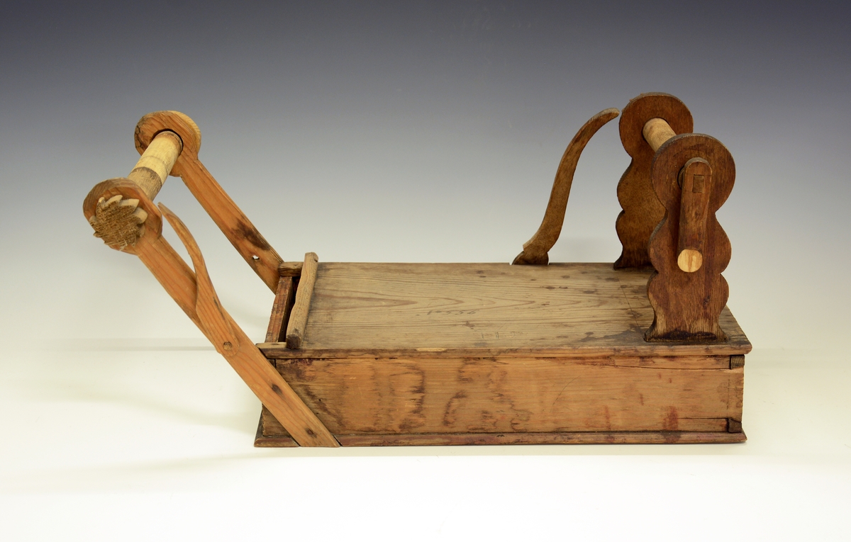Båndvev. Fra protokollen: Baandstol av træ. Bunden med laak, saa der dannes en kasse, hvor vistnok en skuffe er gaat ind.