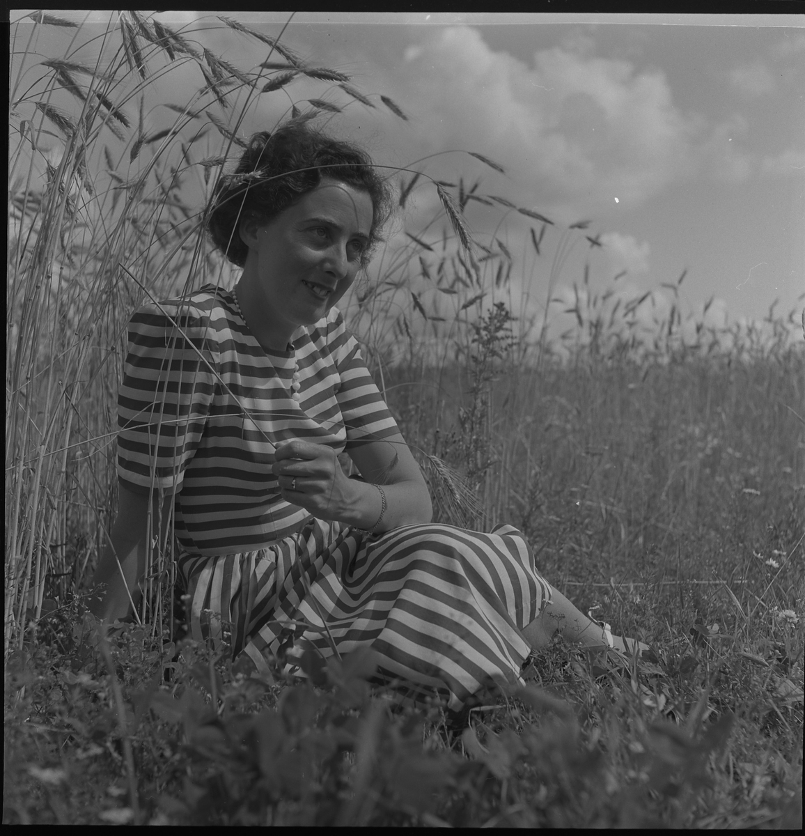 Kerstin Åsén fotograferad vid ett sädesfält. 30 juli 1950