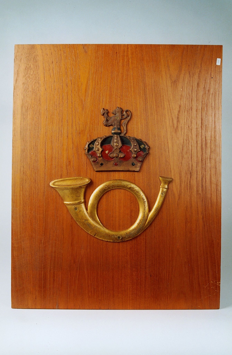 Postmuseet, gjenstander, skilt, postskilt, posthorn og krone med riksløve (postlogo) montert/skrudd fast på en treplate.
