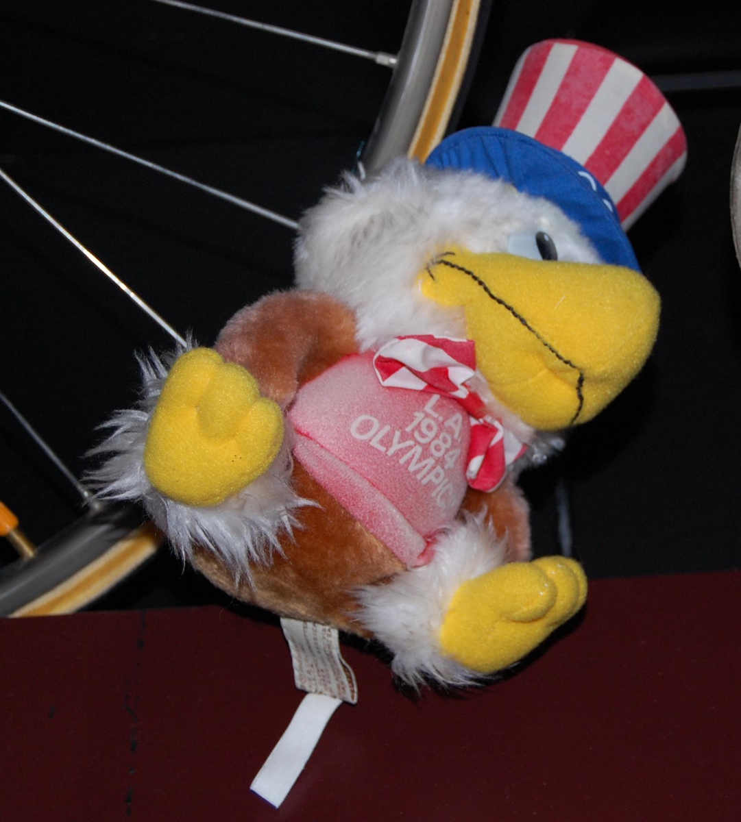 Figur av ørnen Sam; maskoten for de olympiske sommerleker i Los Angeles i 1984. Figuren har på seg en flosshatt.