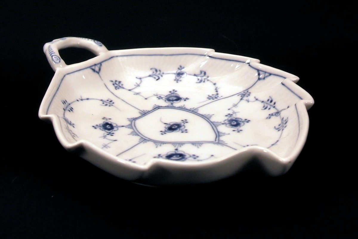 Bladformet skål med hvit, delvis riflet glasur og 'strå' i blått. 