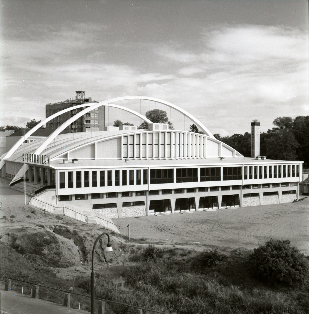 Sporthallen står färdig. Planering av omgivningen pågår.
Sporthallen är en modernistisk och konstruktivistisk byggnad. Den uppfördes 1955-56, arkitekt Hans Westman. Invigningen var den 6 oktober 1956.