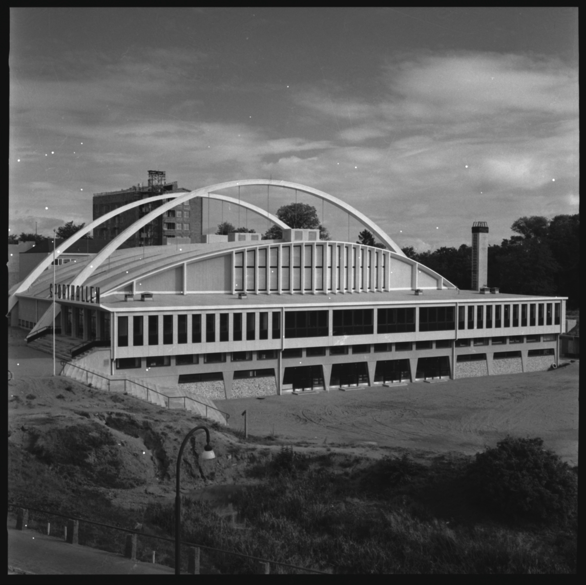 Sporthallen står färdig. Planering av omgivningen pågår.
Sporthallen är en modernistisk och konstruktivistisk byggnad. Den uppfördes 1955-56, arkitekt Hans Westman. Invigningen var den 6 oktober 1956.