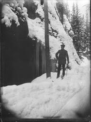 Mann på ski med sekk på ryggen stående ved siden av en telef