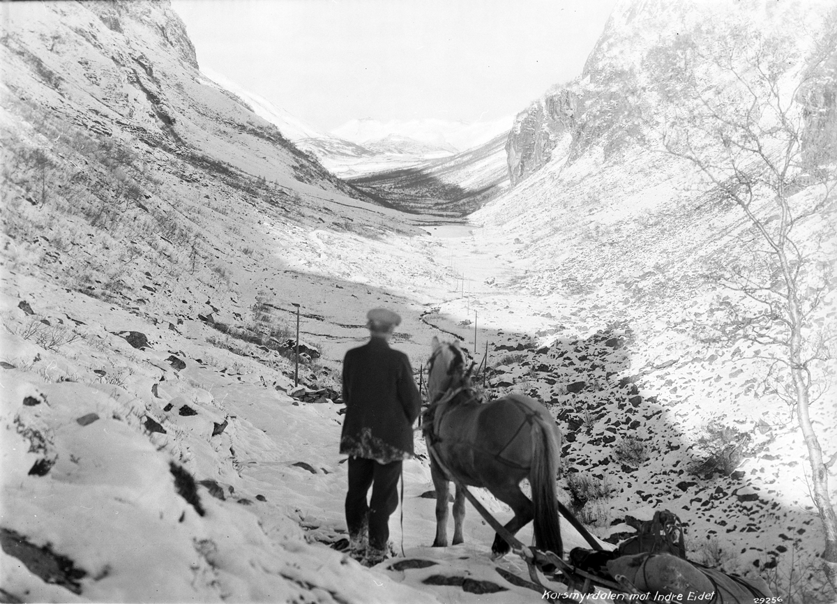Mann og hest på vei gjennom skaret mot Indereidet, snø i fjellet.