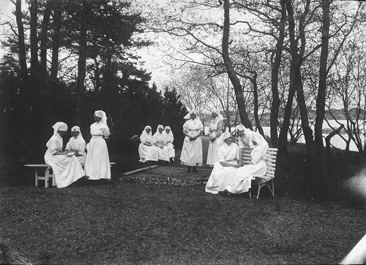 Kvinner fra Sanitesforeningen sitter på benker. Fotografert 1923.
