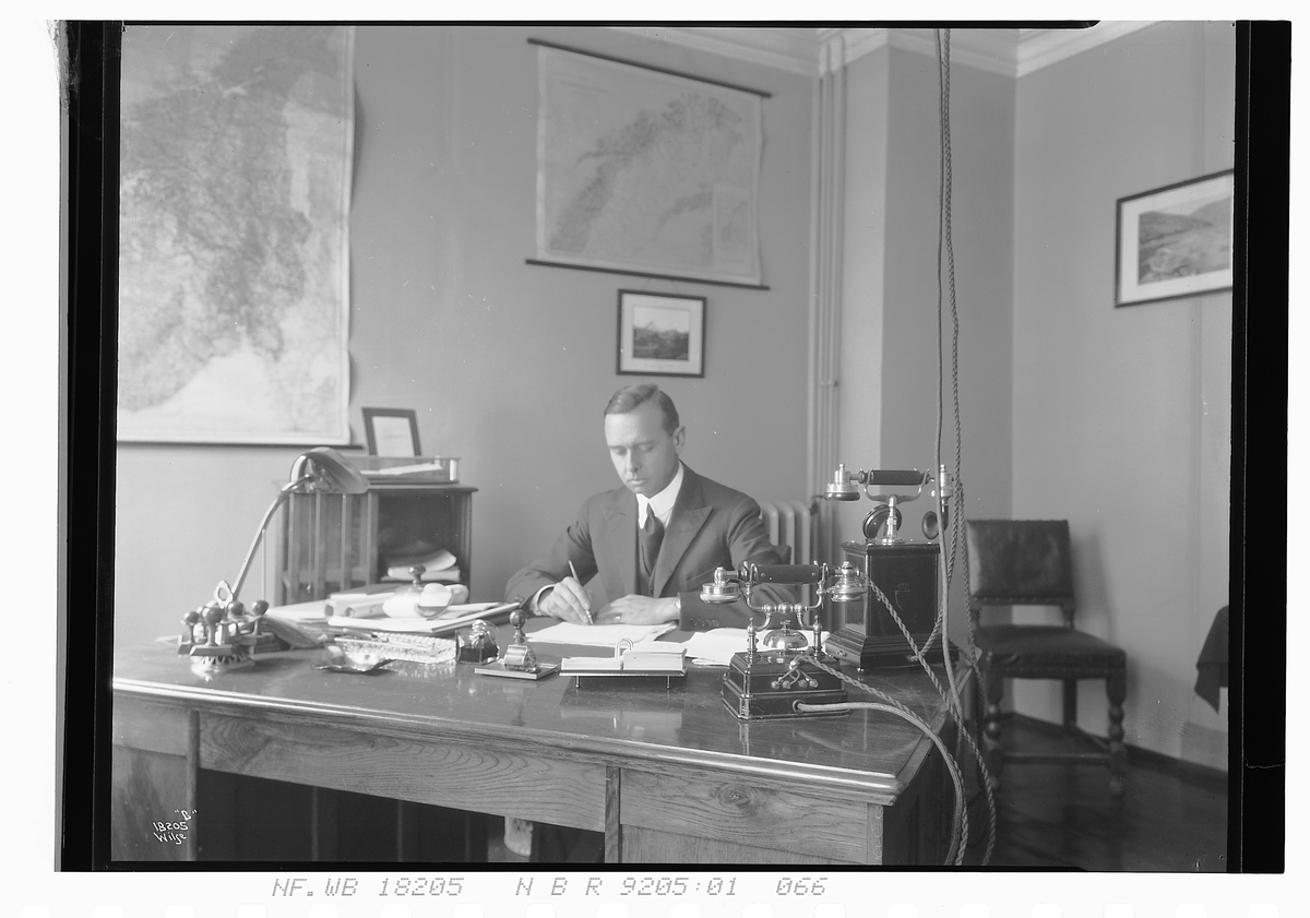 Mann sitter ved skrivebord. Fotografert 1924.