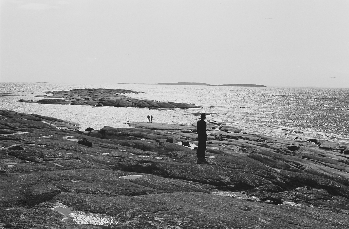Hankø med svaberg ut mot havet, en person nyter utsikten over svabergene og havet, en stille dag i havgapet.