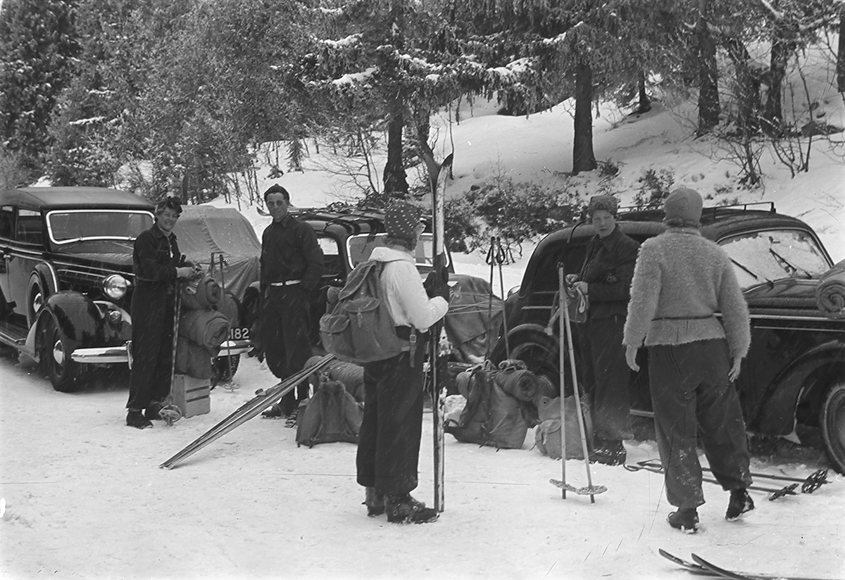 Skigåere utenfor biler (H-5464), klar for hjemtur etter påsken. Fotografert 1940.