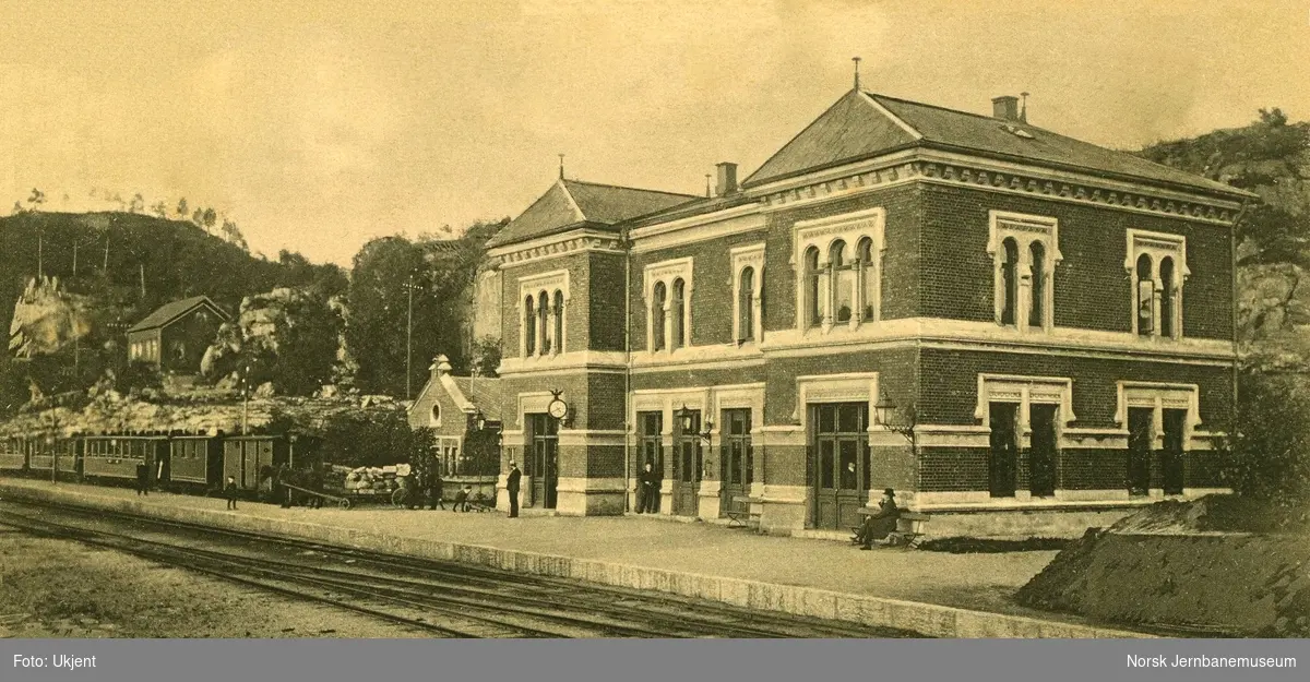 Brevik stasjon, med persontog til venstre. En vognmann med hest og vogn på plattformen
