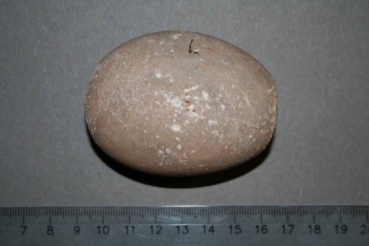 Oval naturlig stein av hard og tettkornet kvartsitt. Med knusespor i begge ender og noe prikkhuggingsspor på den ene bredsiden.