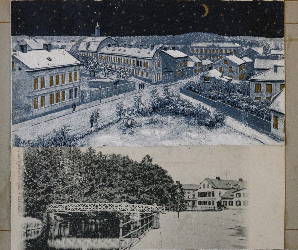 Två beskurna vykort inklistrade i vykortsalbum. Det övre vykortet har motiv av övre Kyrkogatan och Rådhusgatan, Enköping. Fotot är troligen taget från tingshustornet, vilket i så fall daterar bilden till tidigast 1895. Och senast 1898 eftersom det s.k. telegrafhuset i vänster bildkant uppvisar det äldre utseendet. Fotograf Anders Willmanson (1853-1924). I bild ser vi bl.a. rådhuset, huslängan "Långholmen/Strykjärnet", Stadshotellet och i förgrunden den trekantiga ytan som år 1900 iordningställdes till park - i början kallad "Trekanten", sedermera "Afzelii plan". Vykortet är handkolorerat.
Det nedre vykortet har motiv från hamnen/Enköpingsån med gångbron från Munksundet till Hamngatan. Fotot är taget omkring år 1900 av Hilda Isaeus (1858-1917) som arbetade som fotograf i Enköping 1897-1917. Denna sida i albumet har lossnat och ligger löst i pärmen.
