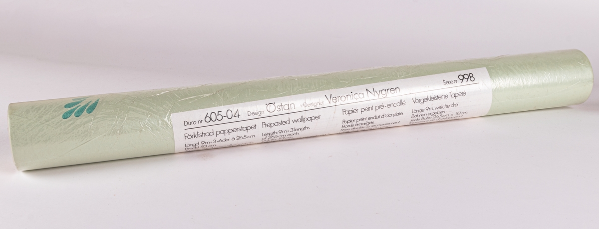 Tapetrulle i originalförpackning. Tillverkad av Duro, designer Veronica Nygren, design: Östan, serienummer: 998. Ljusgrön botten med glest mönster i blågrönt.