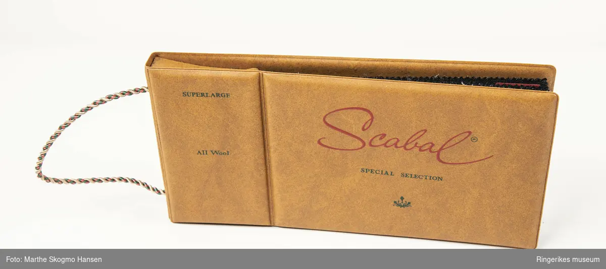 Stoffprøver i ull fra den engelske fabrikanten Scabal, som har produsert kvalitetsstoff til skreddersydde herreklær siden 1938. Alle prøvene har mørke farger og er merket med nummer, gram, cm og serie.