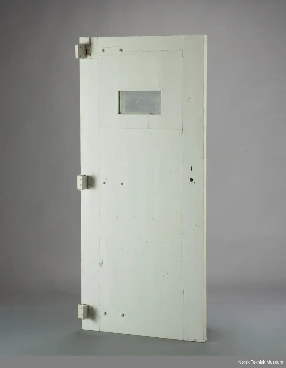 Stor isolatdør med jernbeslag og lite vindu. Håndtak/lås kun på en side av døren (mangler).