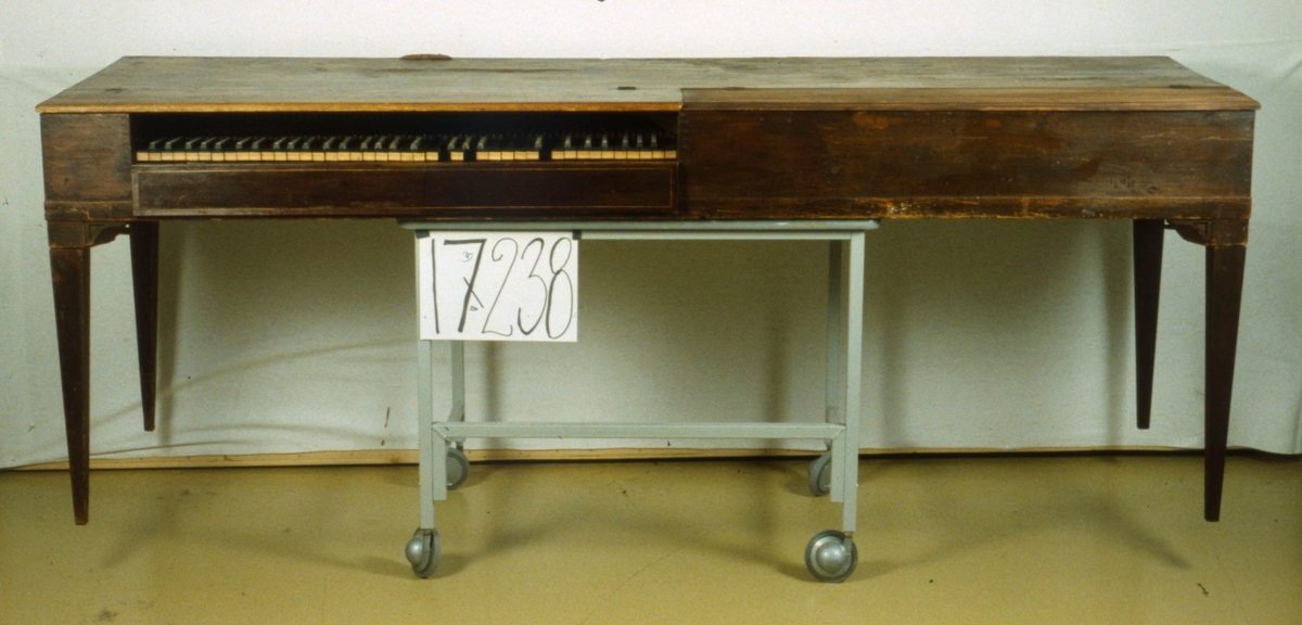 Klavikord, rektangulär mahognyfanerad instrumentlåda med nedtill avsmalnande ben. Hörnklossan utformade som konsoller. Smala inlagda ådror runt klaviaturen. Tangenter belagda med ebenholts och elfenben, några saknas, liksom brädan bakom klaviaturen. Stil: Gustaviansk