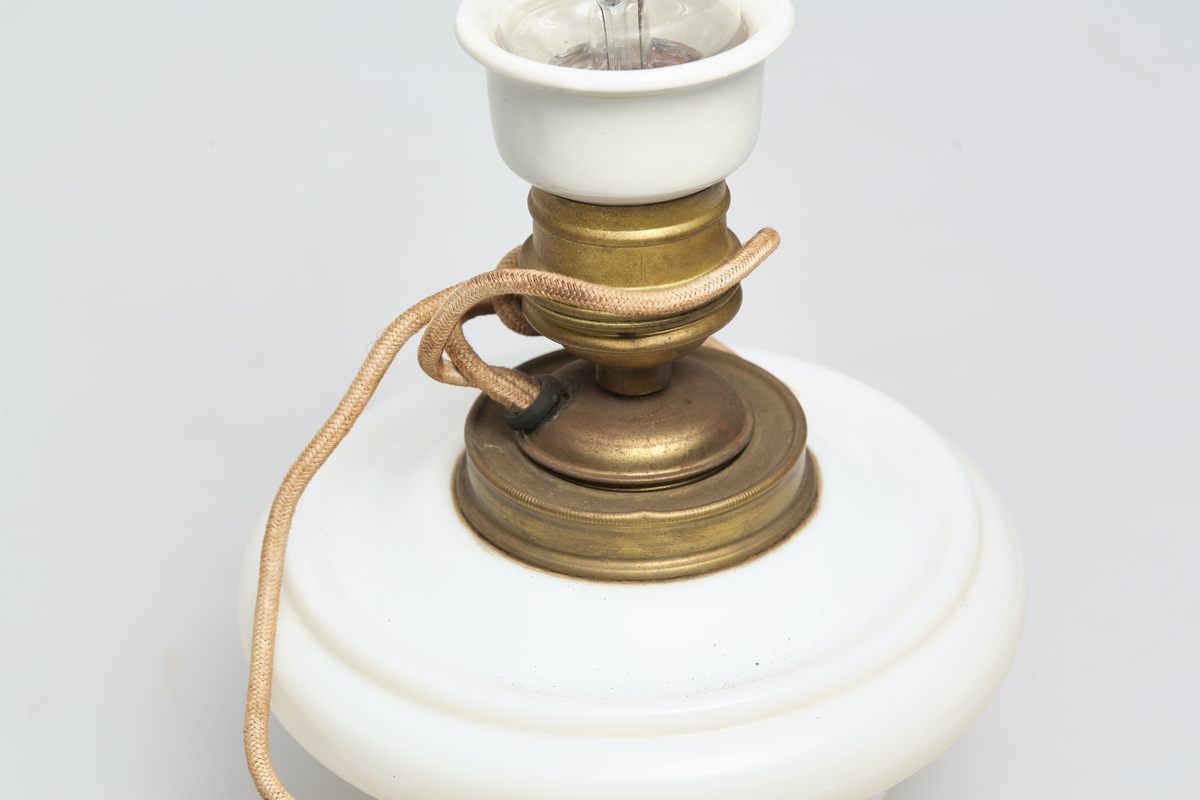 Heisbar parafinlampe ombygd for elektrisitet. Fra Høgbakken. Enkelstående med kuppel bunn i hvit porselen.  Det stikker ut ett tau ut av midten.