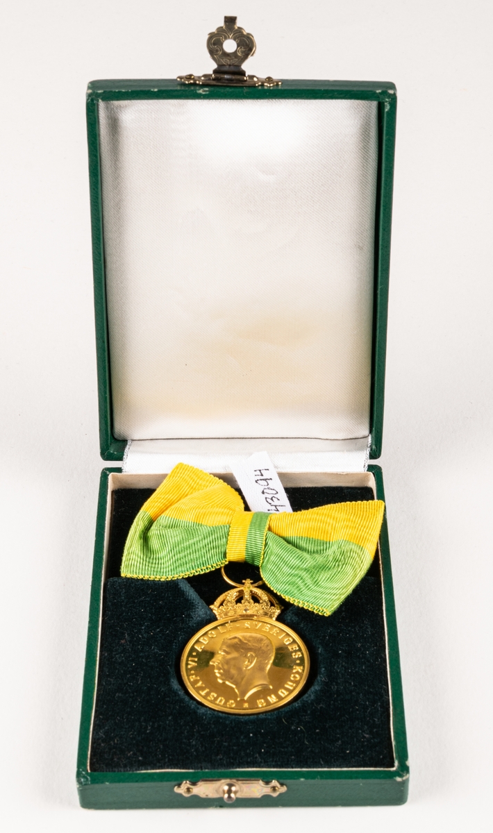 Medalj i etui från Kungliga patriotiska sällskapet till Märta Krantz, för Lång och trogen tjänst på Nordiska museet. Guldmedalj med grönt och gult band.