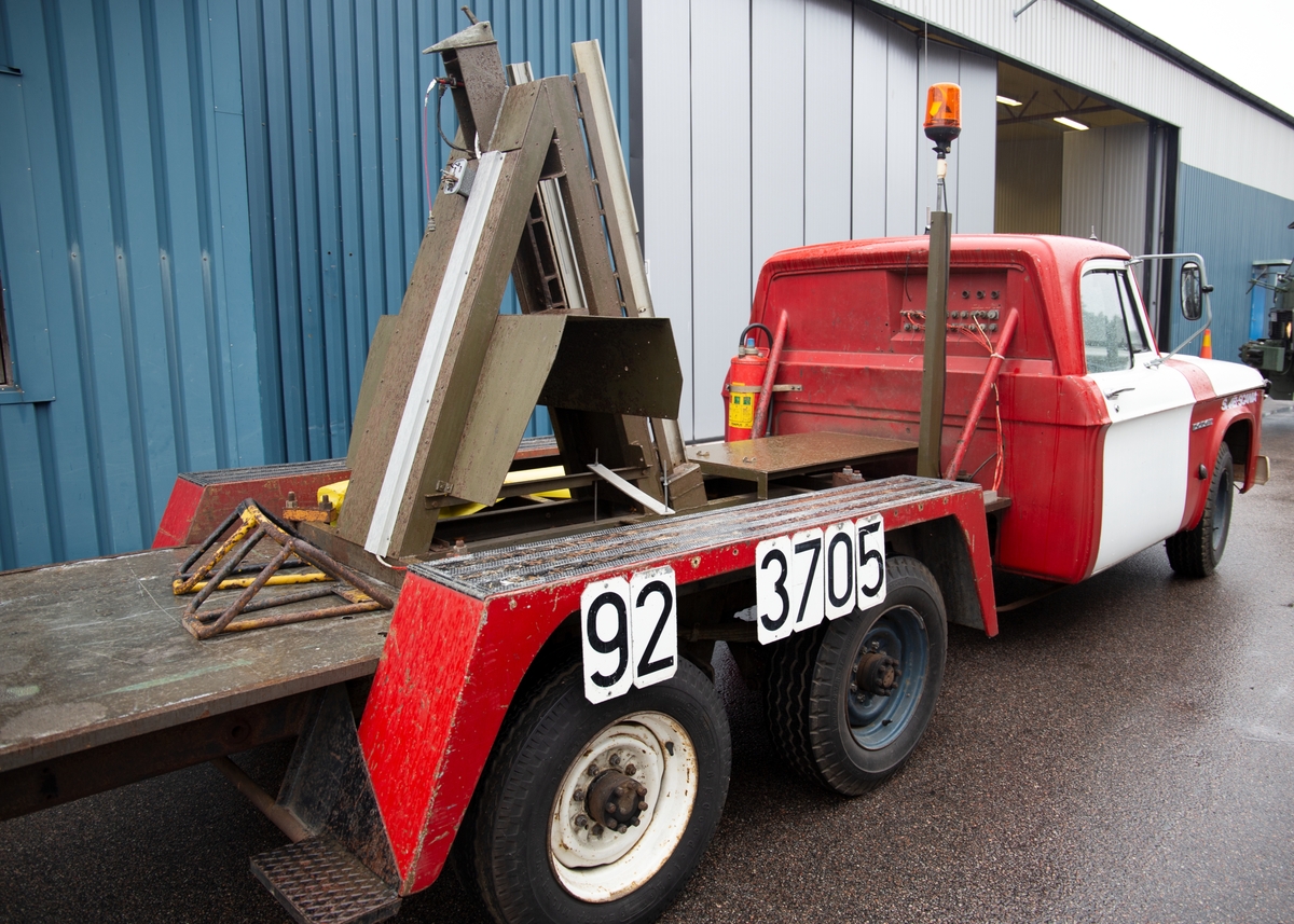 Treaxlad lastbil av märket Dodge ombyggd för test av katapultstolar. På bilens flak är en ramp monterad för testutskjutning av stolar.