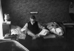 Tormod Berg sitter på sengen og leser "Steinkjærnytt", Vadsø