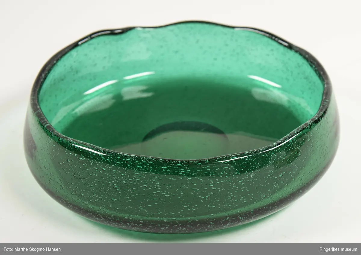 Grønn rund håndblåst glassbolle med ujevn kant. Fra serien Grønland designet av Arne Jon Jutrem for Hadeland Glassverk i 1953.