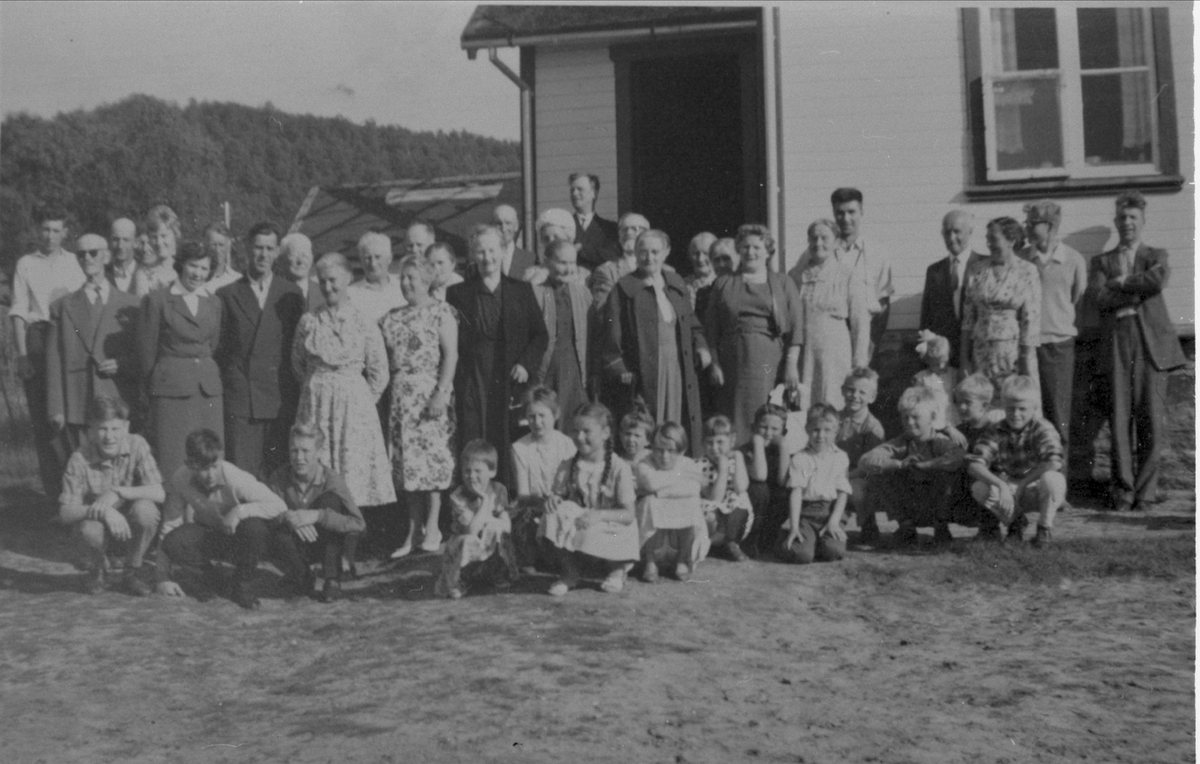 Gruppebilde av voksne og barn, fotografert foran skolehuset på Renså.