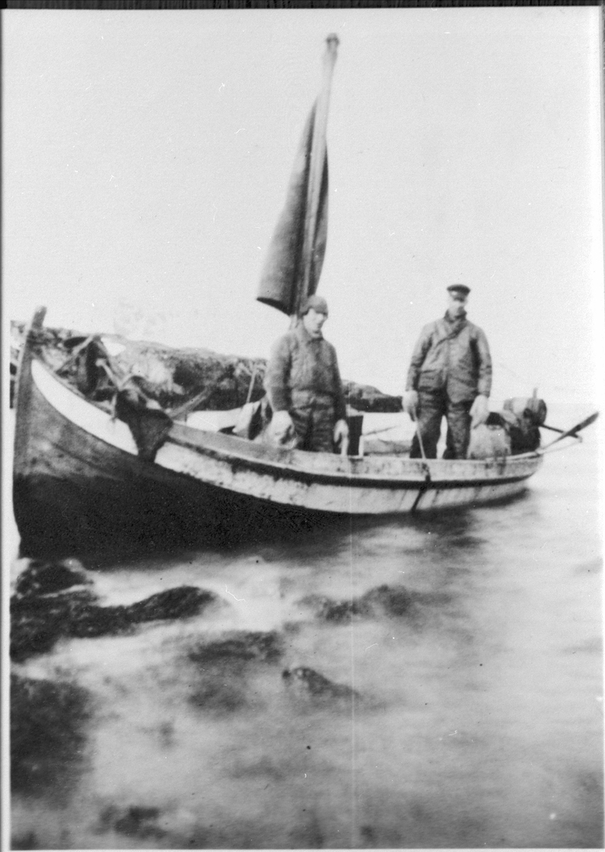 Nordlandsbåt stående i fjæra med to fiskere ombord.
