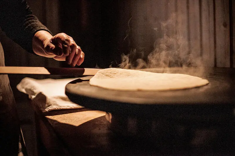 En hånd steker flatbrød på takke