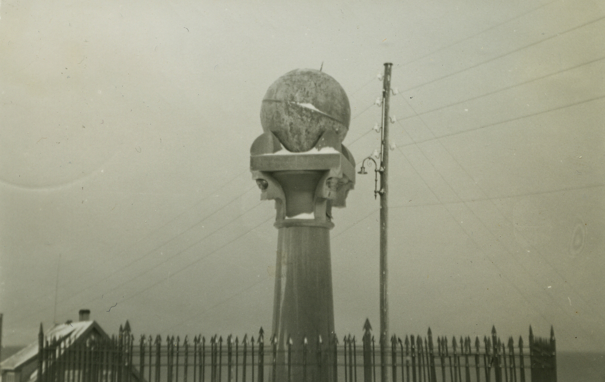 Bildet viser Meridianstøtta på Fuglenes i Hammerfest før våren 1943. På baksiden av fotografiet står det, skrevet for hånd, "Die Weltkugel in Hammerfest". Det er vinter og støtta er omgitt av et stakittgjerde. I bakgrunn ser man en stolpe med elektriske ledninger og gatelys samt et hus.