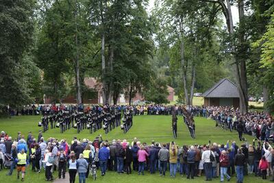 HMK Garden holder drilloppvisning i parken sør for Eidsvollsbygningen, marsjerer i rekker med instrumenter og våpen. Mer enn tusen mennesker står rundt og følger med.