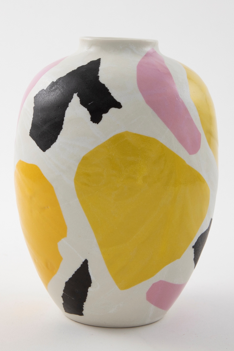 Eggformet porselensvase med kort hals og sirkelrund munning. Hvit glasur og dekaler med abstrakte former i gul, oransje, rosa og svart. Delvis blank glasur på utsiden. Blankglasert på innsiden.