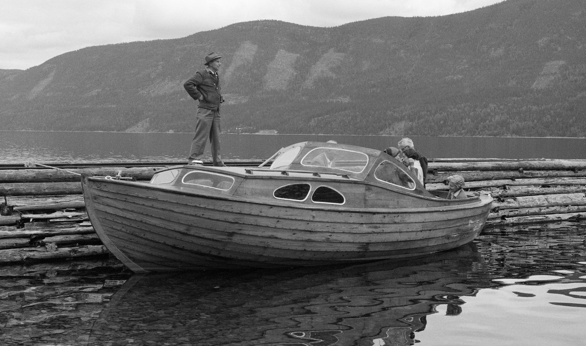 Inspeksjonsbåten till fløtersjefen på Storsjøen, fotografert ved ei steinfylt tømmerkiste, ved Buruvika på innsjøens østside våren 1960. Dette var en klinkbygd trebåt hvor den fremre delen var overbygd mens den bakre delen var åpen.
