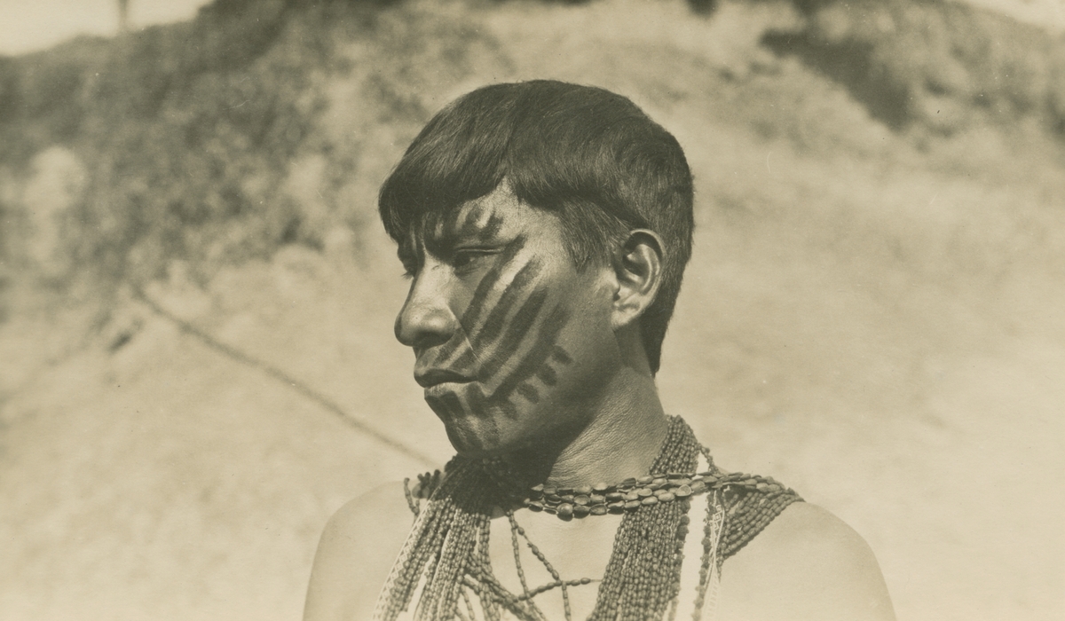 Vykort från Peruexpedition 1920. Porträtt av man med ansiktsmålning och halsband.
