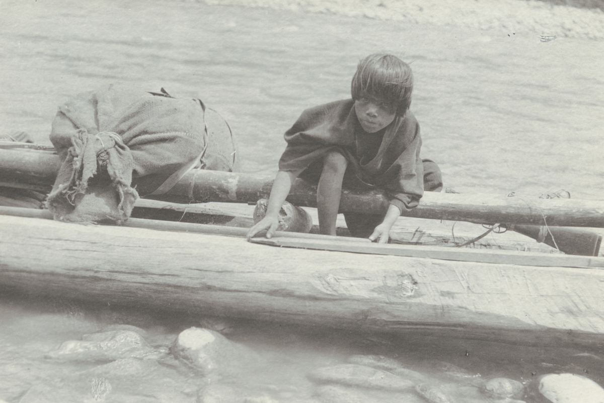 Fotografi från kuvert märkt med "Ernst Nordenskjöld". Motiv av pojke med kanot i vattendrag i djungeln.