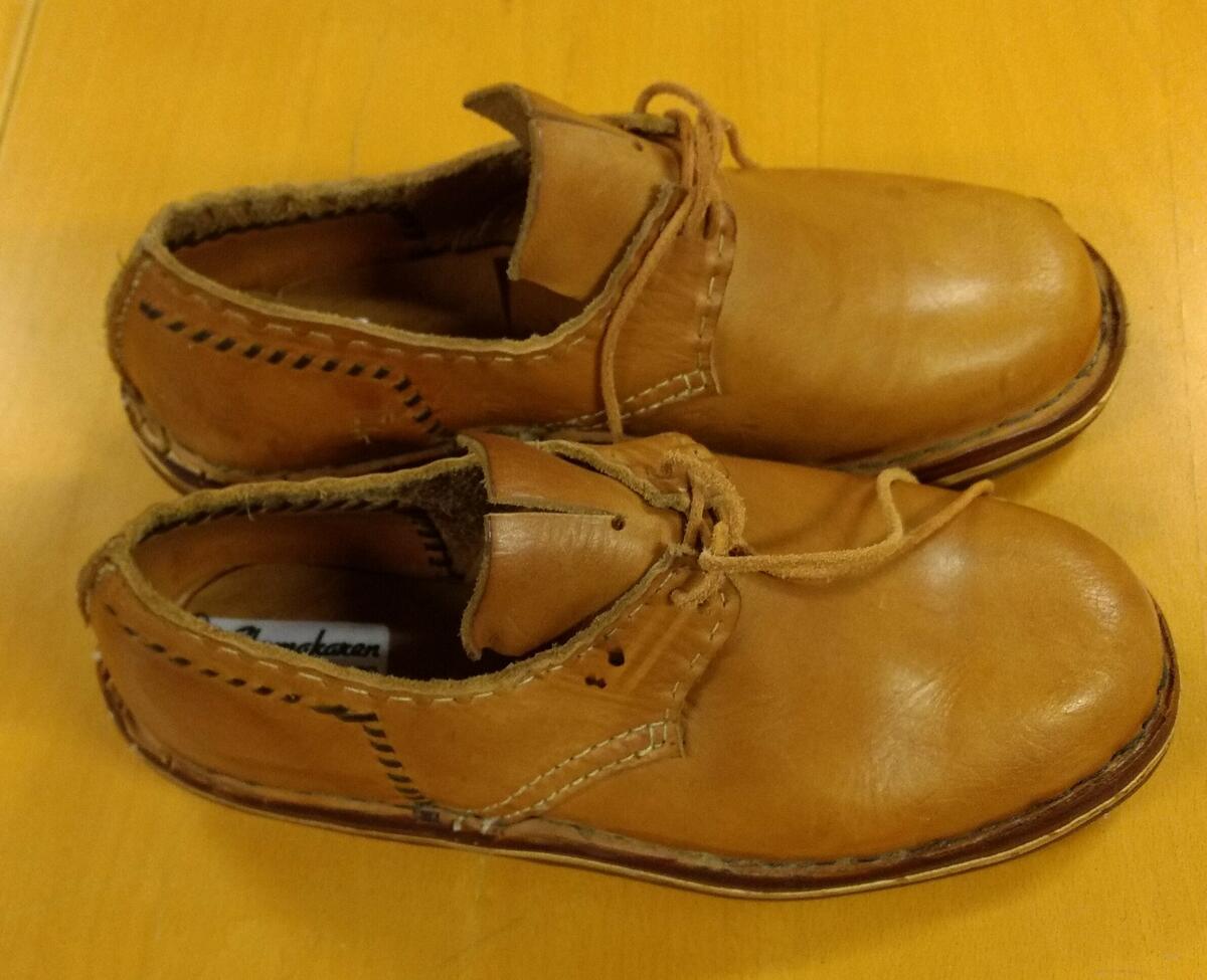 Gåva av skomakarmästare Mogens Hansen, Sundsvall. " Skomakaren, Thulegatan 20, Sundsvall " på etikett inuti varje sko, storlek 38. Modell från c:a 1800 -talet. Mellansula och klack är gjord av näver. Plac: M4BF2.