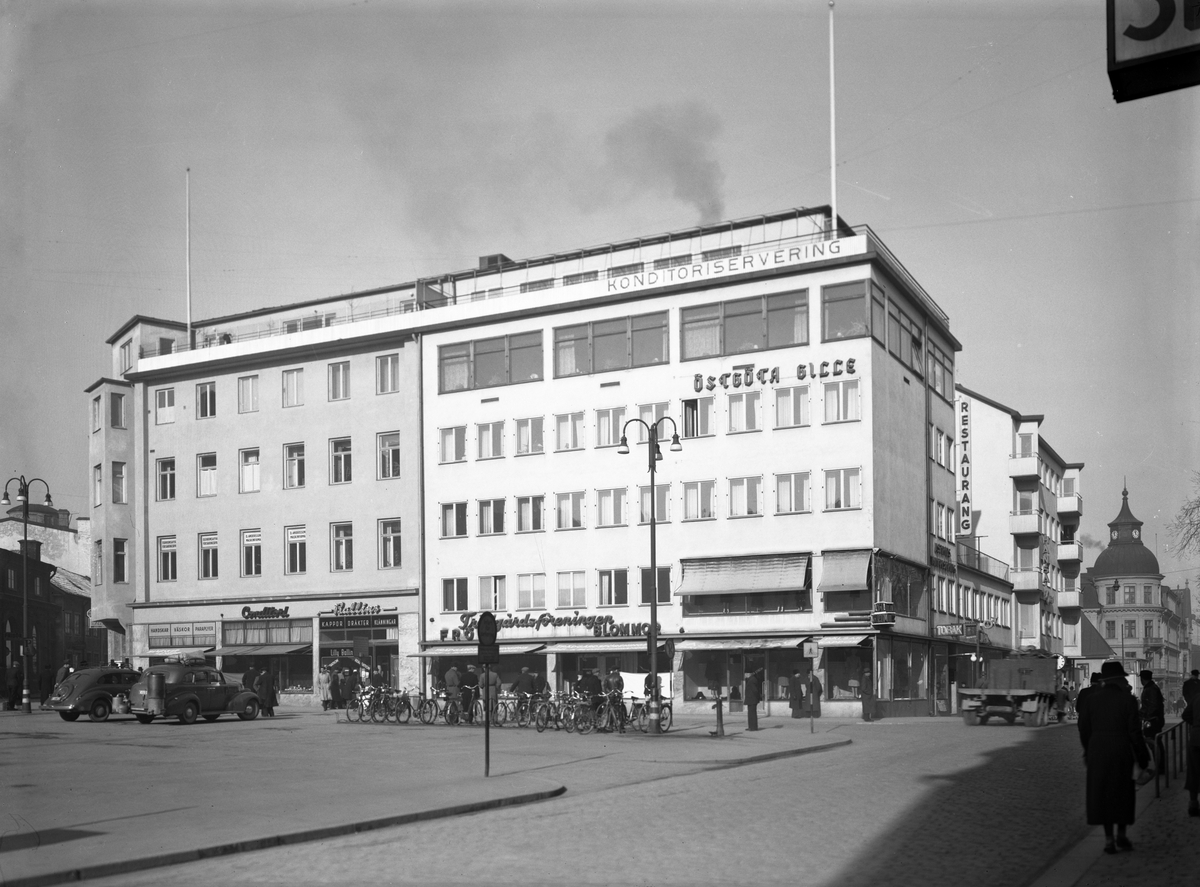 Vy mot det så kallade Centrichuset invid Trädgårdstorget i Linköping. Namnet avser det högra huset, som vid tiden för bilden nyligen uppförts. Huskroppen vänster därom är av äldre datum än vad det ger uttryck för. Det uppfördes rikt utsmyckat redan år 1885, men fasaden har förenklas för att ge torgets norra sida ett mer sammanhållande uttryck. Bilden togs den 7 mars 1944.