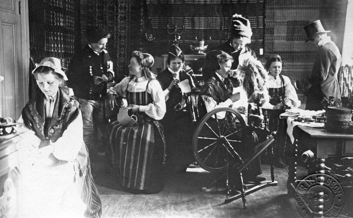 Kvinnor i folkdräkter som arbetar med textilier i Övre Hälsinglands Hemslöjdsförening, Östra skolans lokaler i Hudiksvall, 1910. Stina Rodenstam var den samlande kraften.