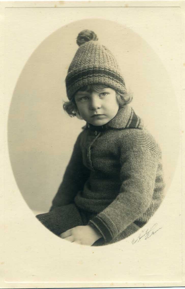 Porträtt av liten pojke i stickad tröja och mössa.