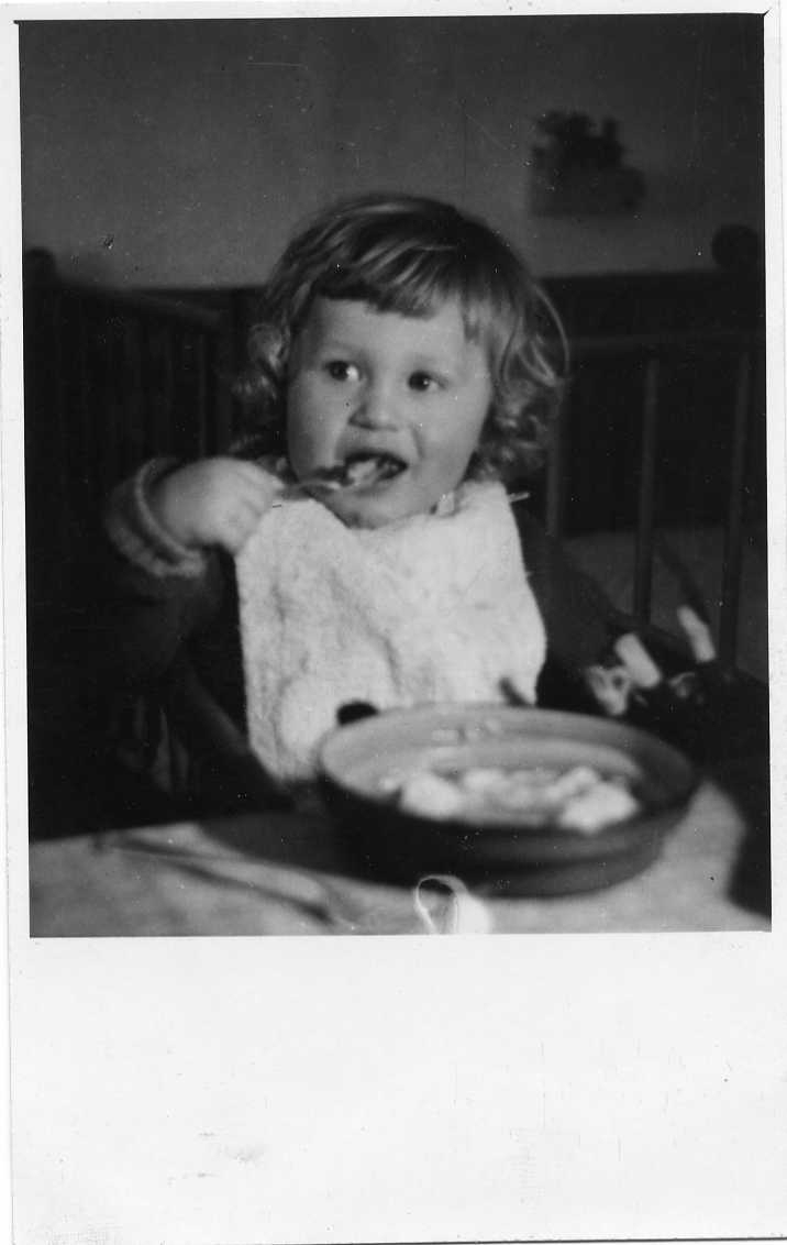 En liten pojke med haklapp som sitter och äter.