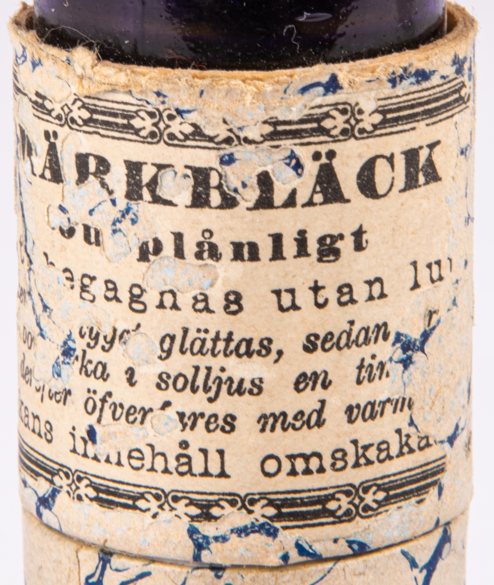 Flaska innehållande märkbläck, skrivbläck, violett. Etikett härstammande från Apoteket Lejonet, Gävle.