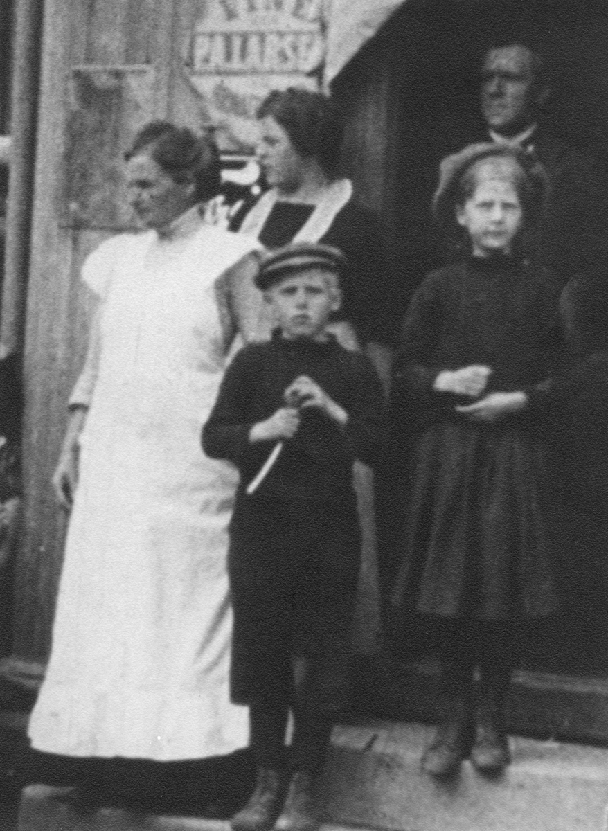 Stillbilde fra Albert Hougners film fra Storgata, Lillehammer 1912. Nærbilde av personer utenfor Karl Halvorsens kolonial i Storgata 115, Lillehammer