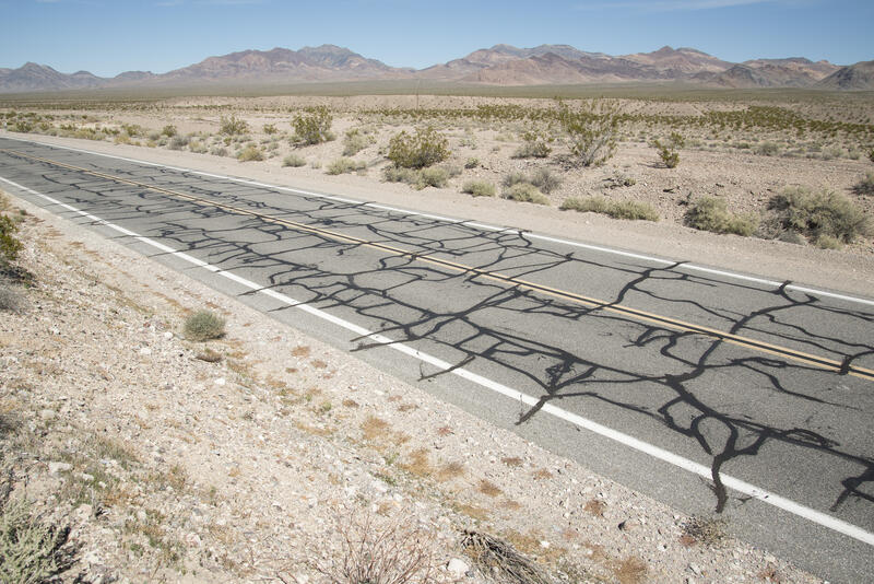 En asfaltert vei skrår gjennom et ørkenlandskap. Fotografi