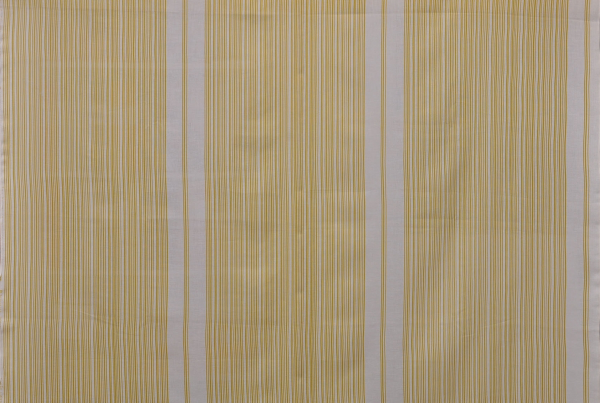 Rayonulltyg, 1960-tal.
"Grafit", design Lisa Gustavsson
Gardintyg på originalbredd 120 cm. Tryckt mönster med gula ränder på vit botten. 
Tvinnat garn i varp och väft.
Rapport - x 40 cm