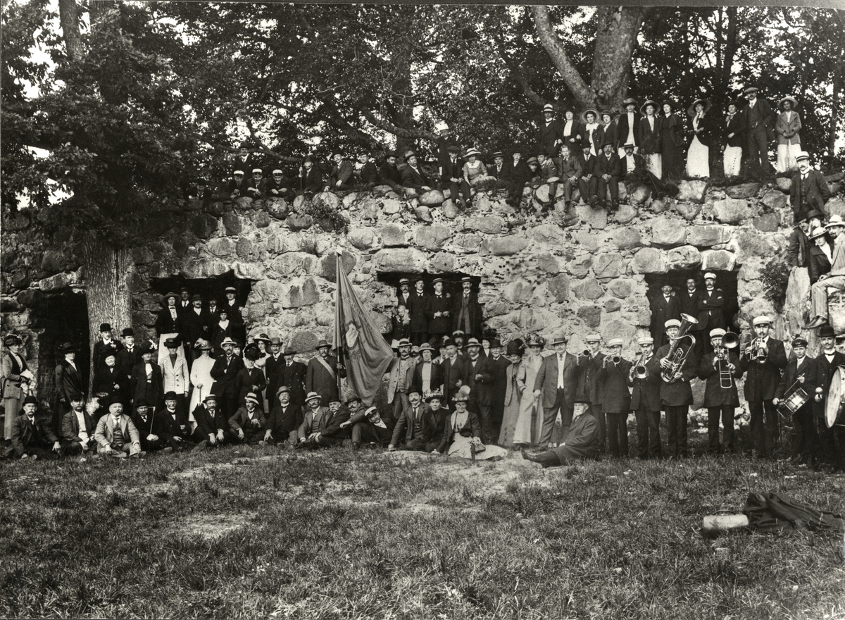 Växjö Fabriks- och Hantverksförening på utflykt till Kronobergs slottsruin, ca 1912.
Gruppfoto från borggården, en del medlemmar har klättrat upp på murarna.