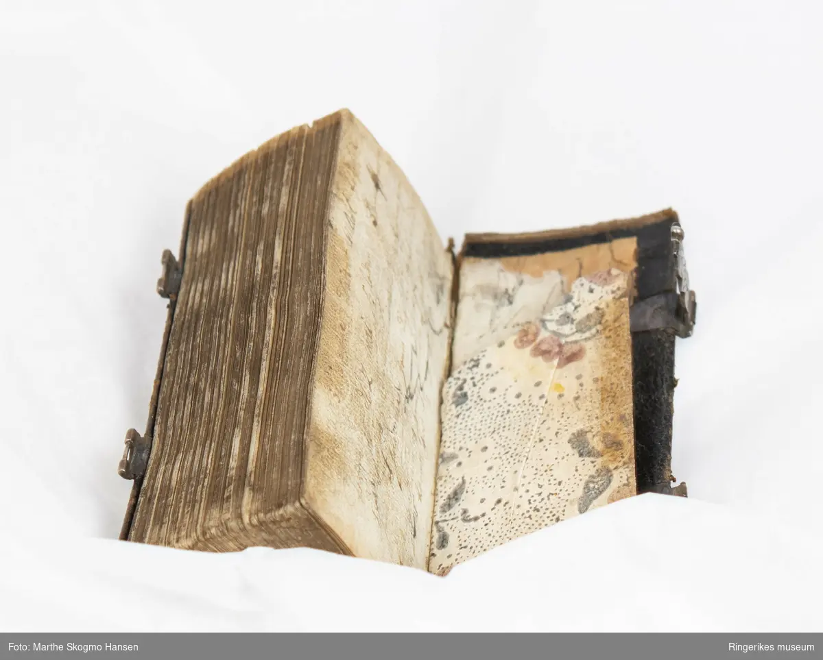 Liten salmebok. 270 sider. Trykket i København i 1762. Uleselig håndskrift på de første og siste sidene. Trepermer trukket med lær på utsidene. Boken lukkes med mønsterdekorerte tinnlåser. Sidenes utsider har innskåret mønster.
